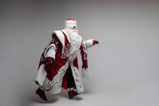 Stock photo of smiling happy Santa in traditional hat with rhinestones and long white beard looking at camera. Cutout on red background. Happiness concept.