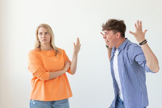 Young hipster guy shouts raising his hands up to his beloved girl showing by hands stop on a white background. Concept of bad relationships and family breakdown