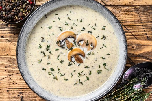 Mushroom cream soup in a plate. Wooden background. Top view.