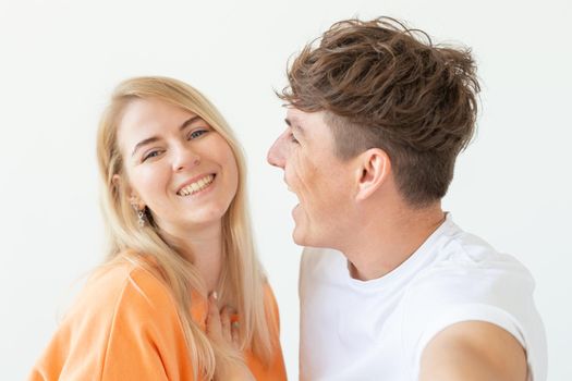 Charming young couple cute blond girl girl take a selfie posing over white background. Concept a young couple of teenagers or millennials In love