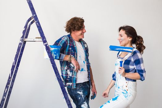 Repair, renovation and love couple concept - young family doing repair and painting walls together and laughing.
