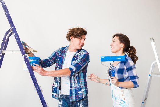 Repair, renovation and love couple concept - young family doing redecoration and painting walls together and laughing
