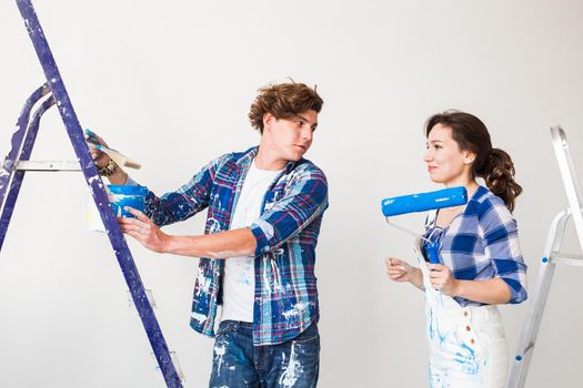 Repair, renovation and love couple concept - young family doing repair and painting walls together and laughing