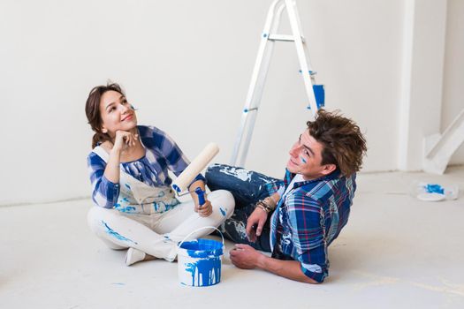 People and interiors concept - Young couple sitting on the white floor.