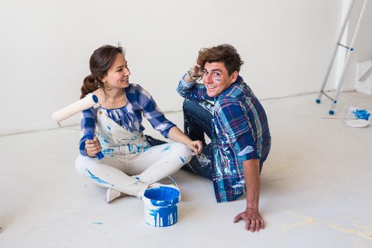 People and interiors concept - Young couple sitting on the white floor.