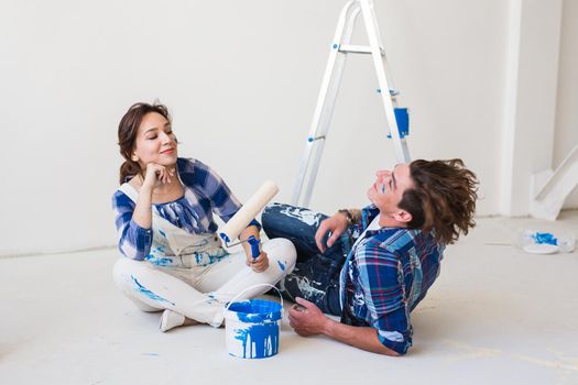 People, redecoration and relationship concept - Young funny couple doing renovation in new apartment.