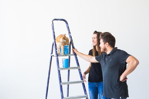 Teamwork and repair concept - young couple with cat doing a renovation in new apartment.