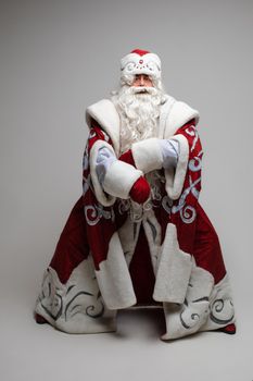 Cool gray haired with long beard Santa Claus in red clothes posing on gray studio background. High quality photo