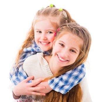 Portrait of two joyful beautiful sisters embracing warmly isolated on white background