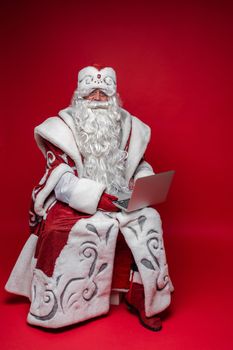 father frost with long white beard serfing internet, picture isolated on red background