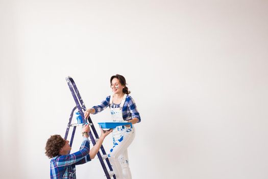 Teamwork, renovation and repair concept - Portrait of funny couple doing redecoration in apartment.