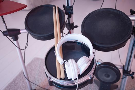 Musical instruments, hobby and music concept - headphone, drumsticks on drum.