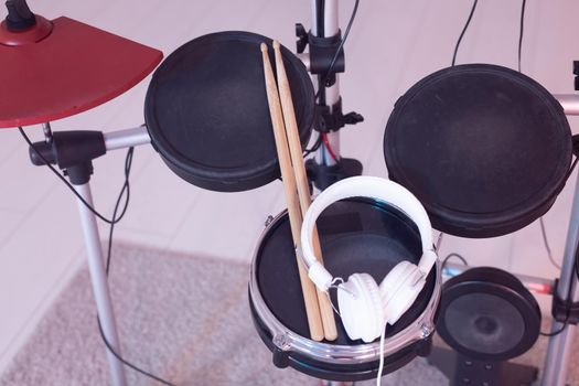 Music, hobby, musical instruments concept - drum with drumsticks and headphones, top view.