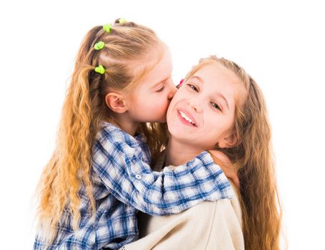 Cute little girl hugging and kissing her older sister, isolated on a white background