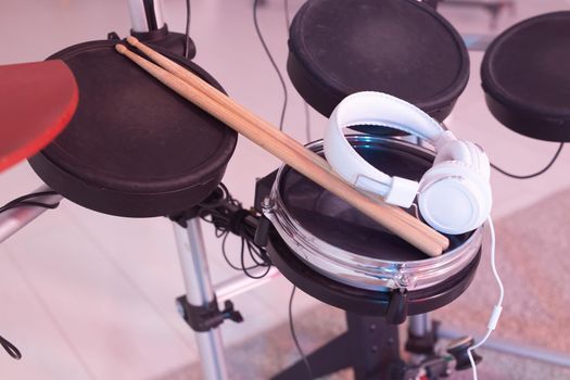 Musical instruments, hobby and music concept - headphone, drumsticks on drum.