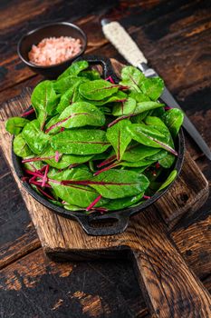 Fresh raw chard leaves, mangold, swiss chard in a pan. Dark Wooden background. Top view.