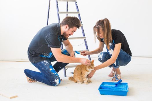 People, redecoration and renovation concept - portrait of couple with cat pour paint.