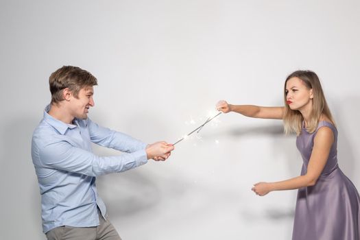 Holidays, party and celebrations concept - young couple with sparklers on white background.