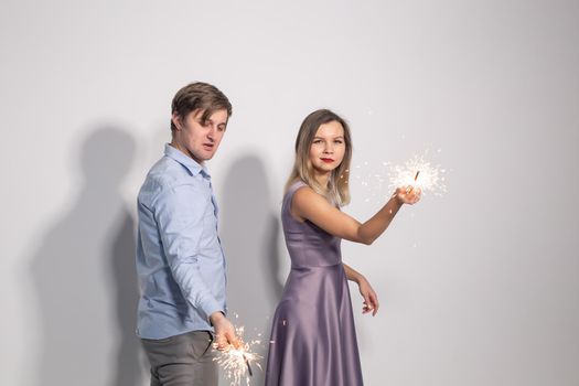 Fun, love and holiday concept - man and woman fooling around with sparklers.