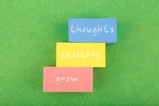Positive affirmation, mental health or quote concept. Grow positive thoughts written on colorful rectangles on green background. Motivational text for inner piece