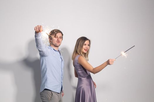 Fun, love and holiday concept - man and woman fooling around with sparklers.