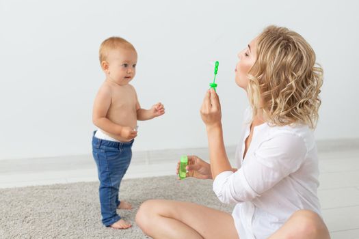 Family and parenting concept - Cute baby playing with her mother on beige carpet.