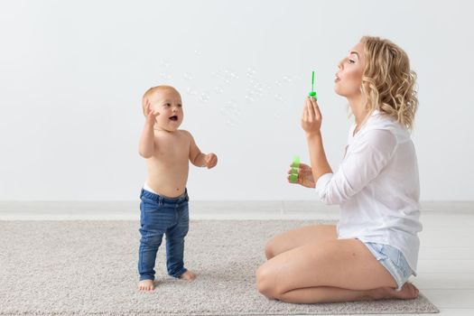 Family and parenting concept - Cute baby playing with her mother on beige carpet.