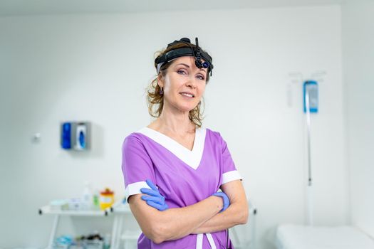 Profession medical industry. Portrait of woman ENT doctor posing in office before examining patient. Physician in bright colored uniform with medical equipment and tools for ENT practice in hospital.