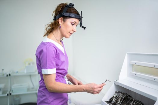 Profession medical industry. Portrait of woman ENT doctor posing in office before examining patient. Physician in bright colored uniform with medical equipment and tools for ENT practice in hospital.