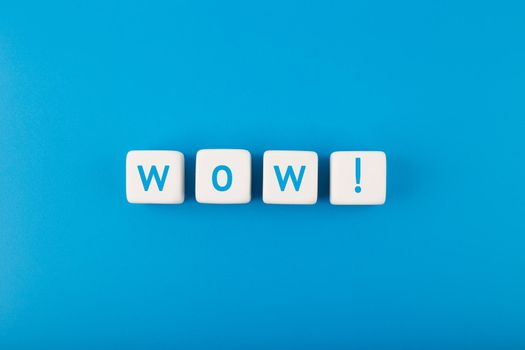 Wow inscription on toy cubes against bright blue background. Colored elegant and minimal style wow concept of expressing emotions and being excited