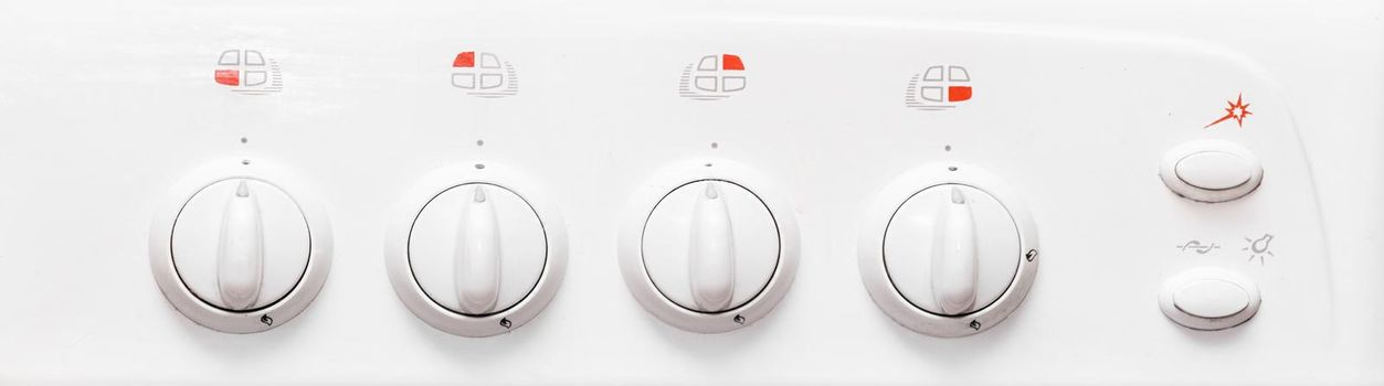 Frontal view of a white gas stove with burner control buttons, close up.