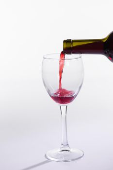 Red wine bottle pour glass on white background.