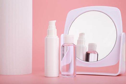 Modern trendy set of two cosmetic bottles next to white column and mirror against bright pink background. Concept of skin care and daily beauty routine