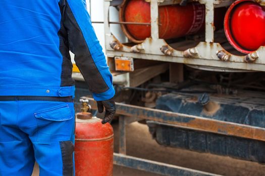 Male industrial worker puts a gas cylinder into a gas machine. Equipment for the safe transportation of propane gas bottles.