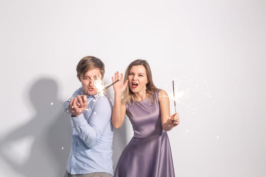 Fun, love and holiday concept - man and woman fooling around with sparklers.