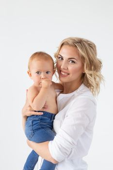 Single parent, motherhood and baby concept - Cheerful mother having fun with her little daughter in the studio, isolated on white background.