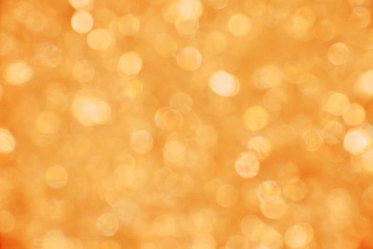 Abstract background of warm summer orange and golden bokeh defocused blurred lights and glitter sparkles