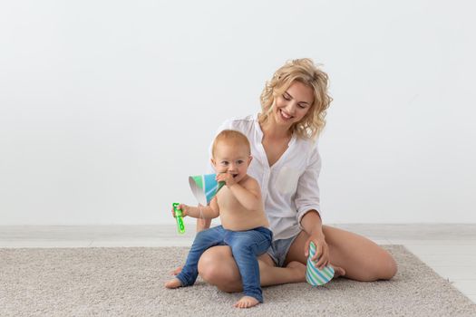 Family and parenting concept - Cute baby playing with her mother on beige carpet.