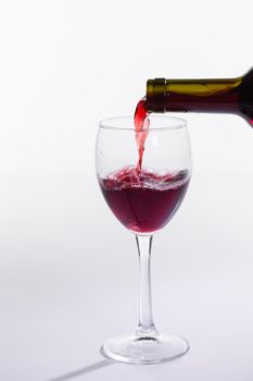 Red wine bottle pour glass on white background.