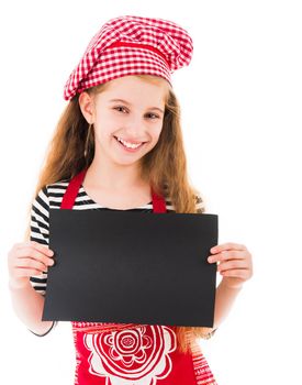 Cute little girl in red kitchen uniform holds horizontal blank black sheet and smiles isolated on white background. Copyspace, space for your text, recipe, advertising, menu
