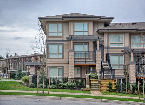 Residential apartment buildings on overcast sky background with concrete pathway in front