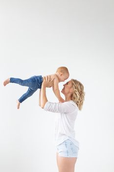 Single parent, motherhood and baby concept - Cheerful mother having fun with her little daughter in the studio, isolated on white background.