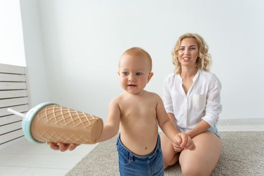 family, child and parenthood concept - happy smiling young mother playing with little baby at home.