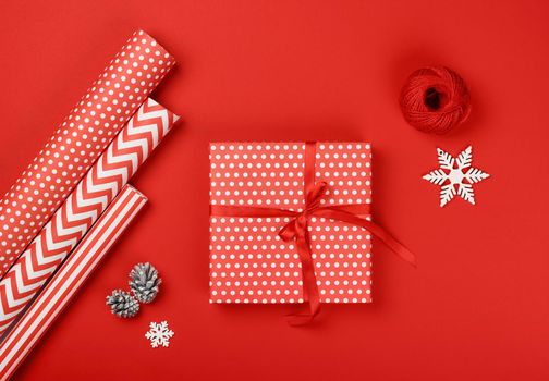 Close up packing and wrapping Christmas gifts with red and white paper, table top view, flat lay