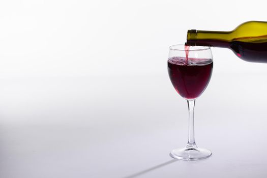 Red wine bottle pour glass on white background.