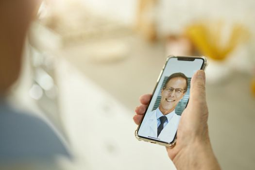 Fragment photo of eldelry man holding smartphone while having medical consultation with doctor online