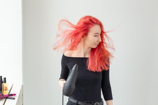 Hairdresser, beauty salon and people concept - young woman hair stylist with hair dryer on white background.