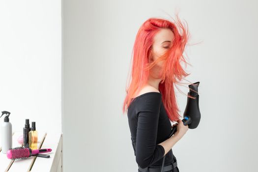 Stylist, fashion, hairdresser, people concept - woman drying her colored hair.