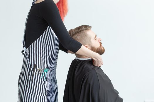 Hairdresser, hairstylist and barber shop concept - woman hairstylist cutting a bearded man.