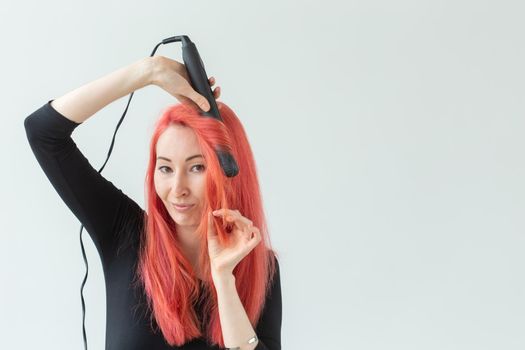 Style, fashion, hairdresser and people concept - stylish red-haired woman with curling iron on white background.